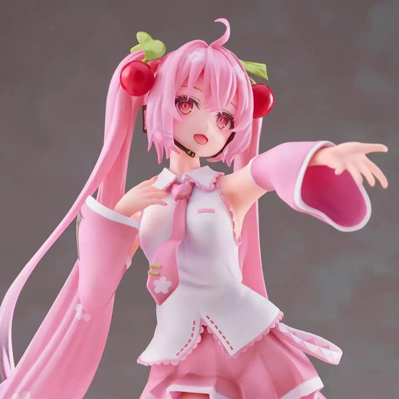 Figura de uma personagem de anime Hatsune Miku Sakura com cabelo rosa, vestindo roupa rosa e apontando com expressão animada.
