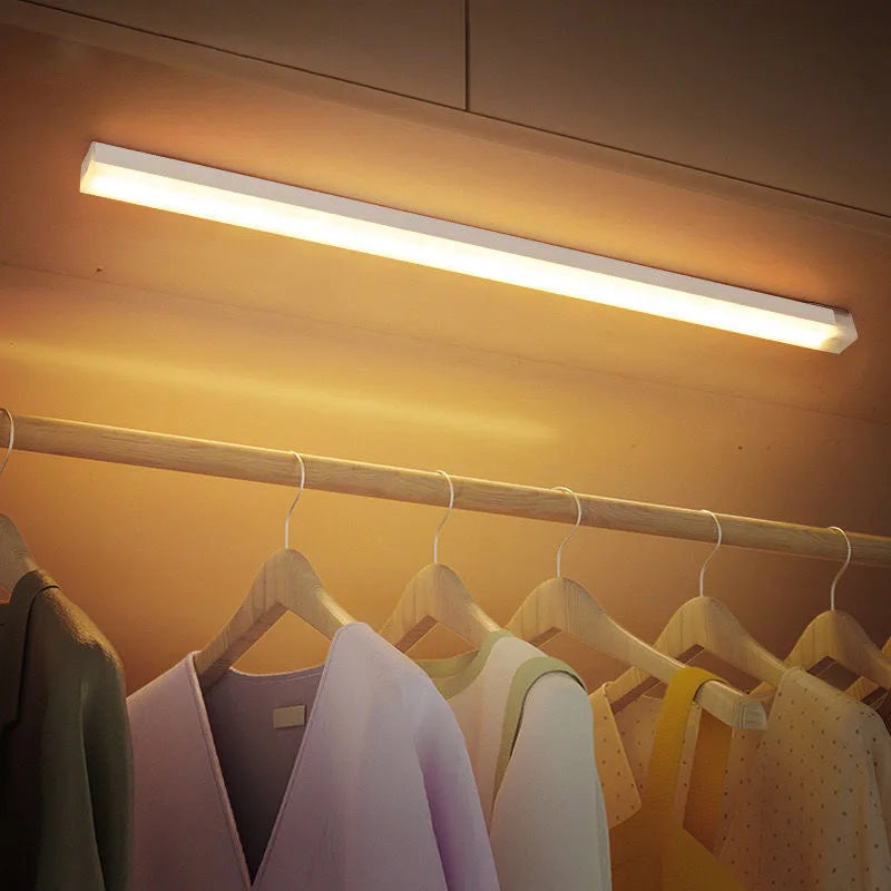 Imagem de roupas coloridas penduradas em cabide com iluminação de LED de cima, ambientes internos aconchegantes e organizado.